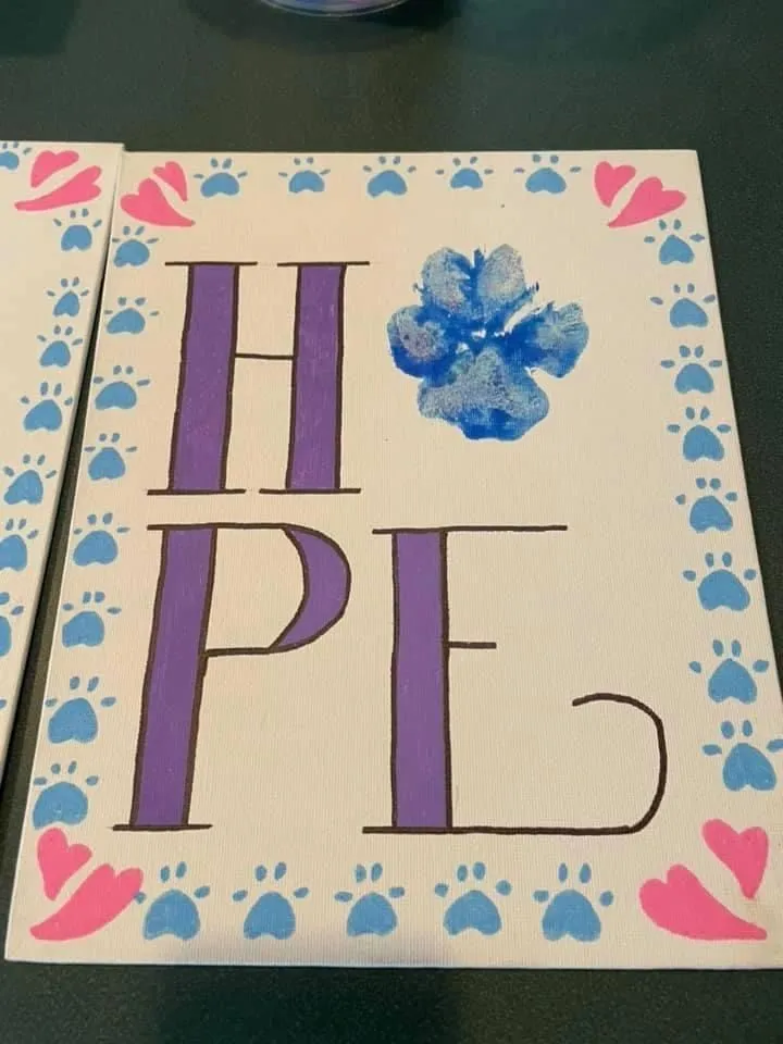 A hand-painted sign reading HOPE with paw prints